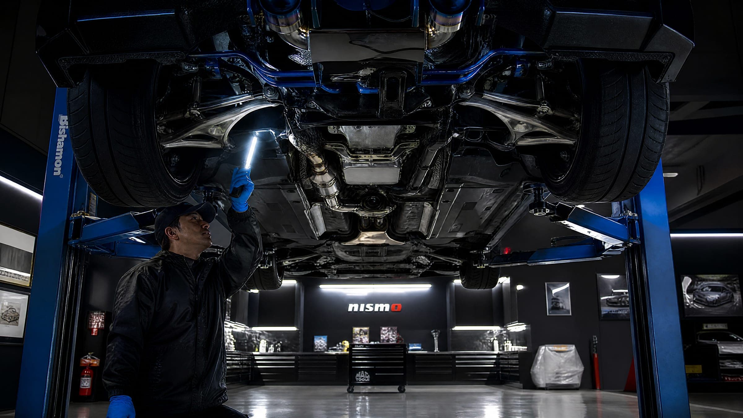 A technician inspecting the underbody on the hoist